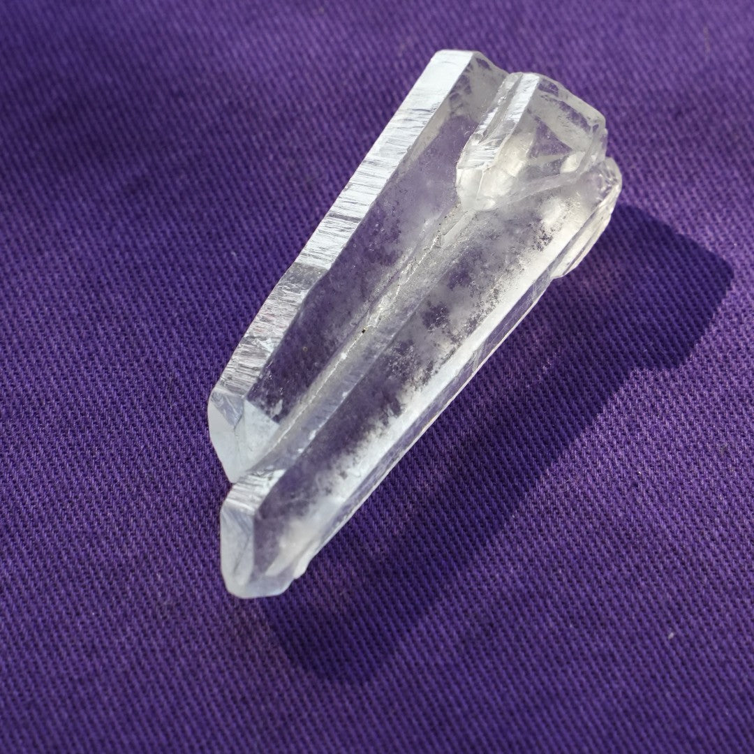 A single clear quartz point on purple cloth