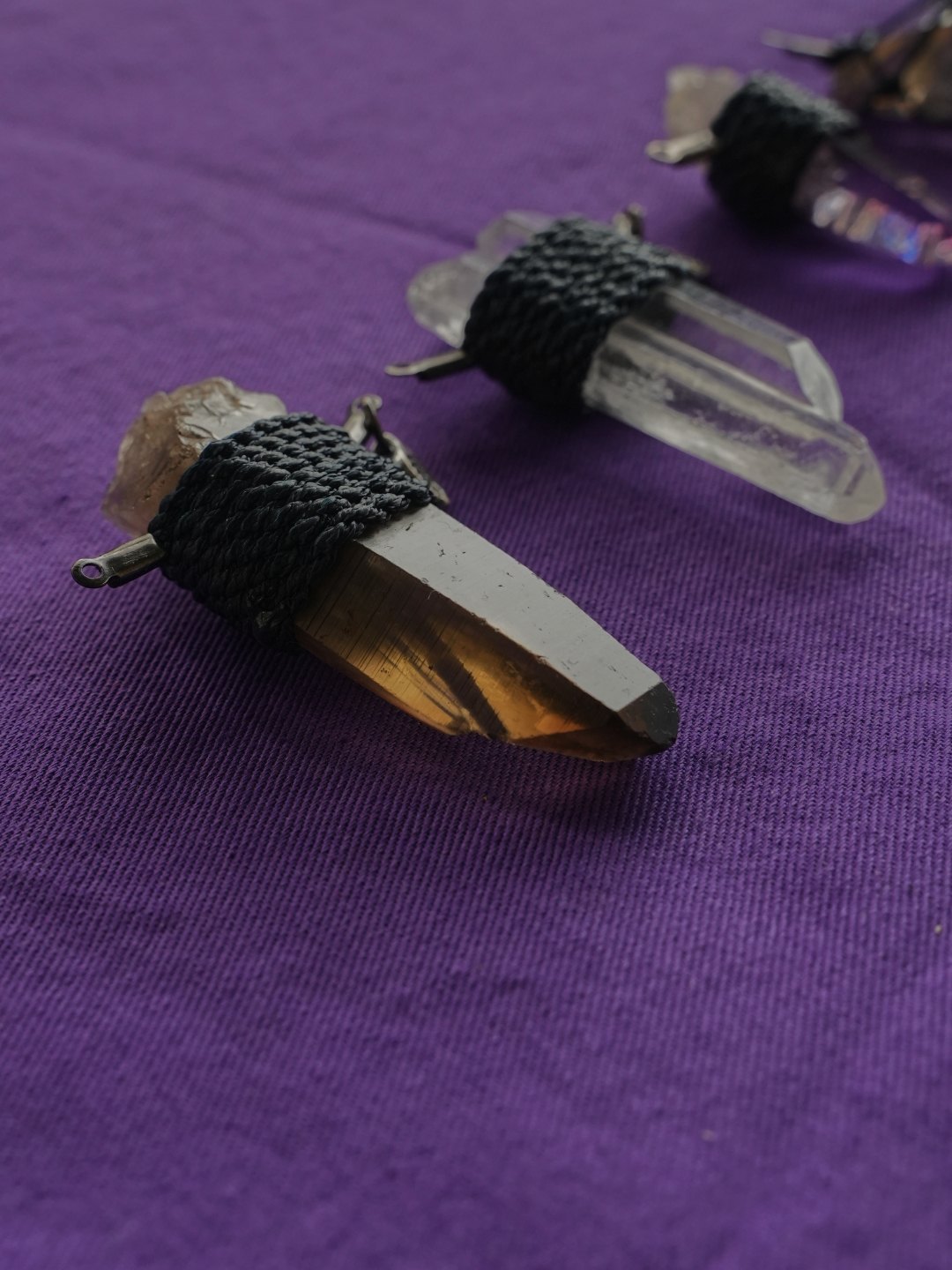 A cord-wrapped smokey quartz pendant on purple cloth