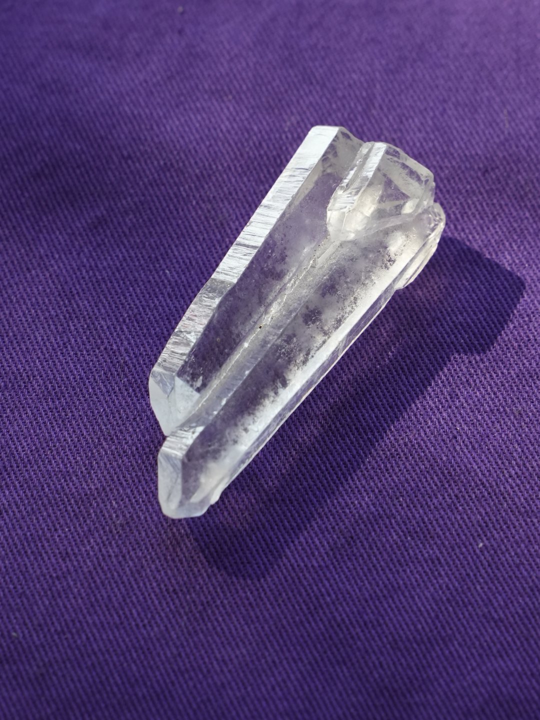 A clear quartz point on purple cloth